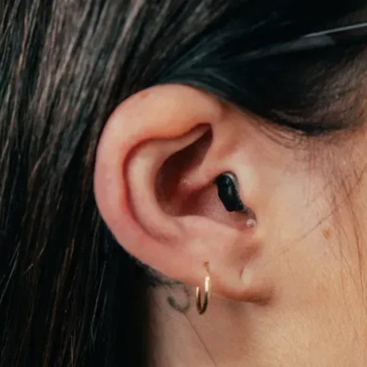 A completely-in-canal hearing aid, sitting deep in the canal with only a small removal cord visible
