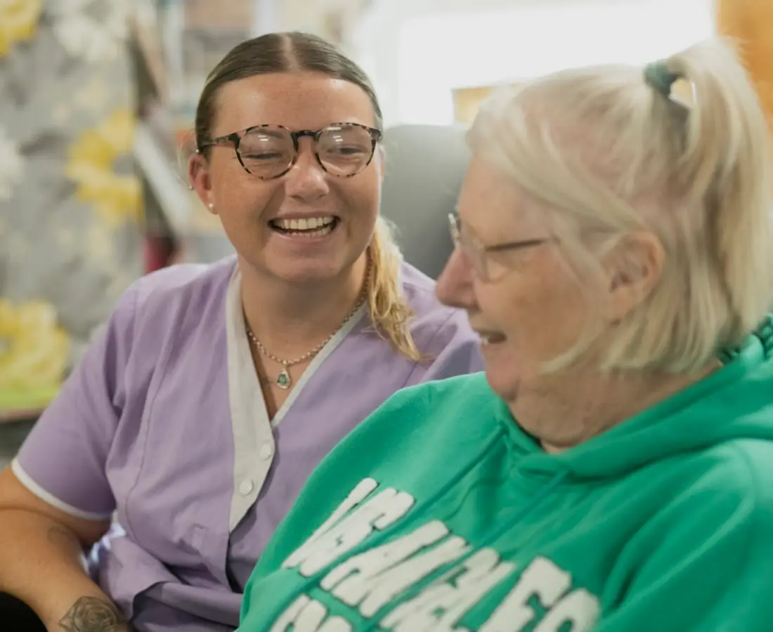 A caregiver sharing a warm moment with an older adult during an in-home visit